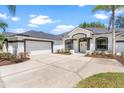 Exterior of a bright home featuring a large driveway, two-car garage and manicured landscaping at 39634 Harbor Hills Blvd, Lady Lake, FL 32159