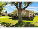 Single-story home features a well-manicured lawn, mature trees, and lush landscaping at 4835 Calasans Ave, St Cloud, FL 34771