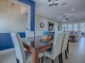 Stylish dining room with seating for six, set against a blue accent wall leading to a comfortable living area at 4976 Sandpiper Dr, Oxford, FL 34484