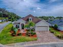 Inviting single-story home featuring a paver driveway, lush landscaping, and an attached two-car garage at 4976 Sandpiper Dr, Oxford, FL 34484