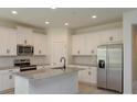 Modern kitchen with white cabinetry, stainless steel appliances, granite countertops and an island with a sink at 5045 Balsam Falls Rd, Deland, FL 32724