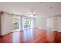 Airy living room boasts red wood floors, a ceiling fan, natural light, and sliding glass door leading to balcony at 601 W Old Hwy 441 # 11B, Mount Dora, FL 32757