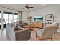 Comfortable living room with neutral colors, ceiling fan, and sliding door to the screened porch at 7627 Taormina Way, Clermont, FL 34714