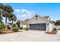 View of the home's 2-car garage and beautifully paved driveway with mature landscaping at 815 Cortez Ave, The Villages, FL 32159