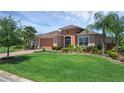 Well-maintained home with a lush green lawn, colorful landscaping, and a brick paver driveway at 453 Treviso Dr, Poinciana, FL 34759