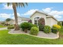 Beautifully landscaped yard with green lawn, palm tree, and flowering shrubs surround this bright single-story house at 1521 Southport St, The Villages, FL 32162