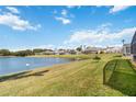 A serene lake view is showcased behind a lush, green lawn and a row of screened-in lanais at 157 Julliard Blvd, Davenport, FL 33897