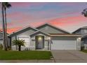 Charming single-story home at sunset featuring a well-manicured lawn, a two-car garage, and a welcoming front entrance at 157 Julliard Blvd, Davenport, FL 33897