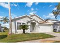 Well-maintained home with a manicured lawn, a palm tree, and a two-car garage, offering curb appeal at 157 Julliard Blvd, Davenport, FL 33897