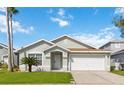 Charming single-story home with a well-manicured lawn, attached garage and tropical landscaping at 157 Julliard Blvd, Davenport, FL 33897