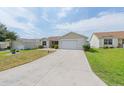 A home with a long driveway and a well-manicured front lawn at 17068 Se 96Th Chapelwood Cir, The Villages, FL 32162