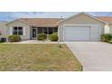 Inviting one-story home with a well-kept lawn, attached garage, and screened in porch at 17068 Se 96Th Chapelwood Cir, The Villages, FL 32162