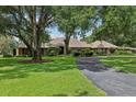 Charming single-story home with mature trees, lush lawn, and a circular driveway providing ample parking space at 1930 Country Club Rd, Eustis, FL 32726