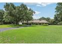 Spacious lawn featuring a well-manicured landscape with mature trees leading to a single-story home at 1930 Country Club Rd, Eustis, FL 32726