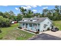 Charming home has a light blue exterior, dormer windows, front porch, and surrounding green landscape at 19703 Lake Lincoln Ln, Eustis, FL 32736