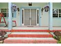 Inviting front porch with decorative pillars, hanging floral baskets, and red brick steps at 19703 Lake Lincoln Ln, Eustis, FL 32736