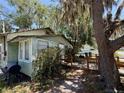 Cozy home exterior, featuring a small wooden deck and a charcoal grill, shaded by mature trees at 2001 Bates Ave, Eustis, FL 32726