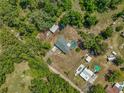 Aerial view of a home with a pool surrounded by lush greenery and a detached garage at 27610 Debbie Rd, Okahumpka, FL 34762