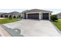 Wide driveway leading to a two-car garage, complemented by a well-manicured lawn and decorative landscaping at 2988 Sentell St, The Villages, FL 32163