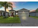 Charming single-story home with well-maintained lawn, colorful landscaping and neutral color palette at dusk at 3060 Neverland Dr, New Smyrna Beach, FL 32168