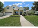 Traditional home with a two car garage, green shutters, and manicured landscaping at 397 Anderson Dr, Tavares, FL 32778