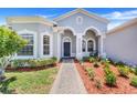 Inviting front entrance with brick walkway, lush landscaping, arched entryway, and a cozy bench at 4716 Block Island Ln, Clermont, FL 34714