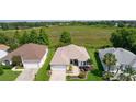 Aerial view of single-story home with well-manicured lawn, attached garage, and a view of the pond at 541 Carrera Dr, The Villages, FL 32159