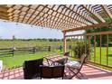 Cozy outdoor patio area with a pergola, a table, chairs, and a view of the lush green lawn at 541 Carrera Dr, The Villages, FL 32159