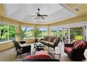 Bright sunroom featuring ample seating, a ceiling fan, and large windows with views of the lush backyard at 541 Carrera Dr, The Villages, FL 32159