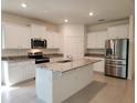 Bright kitchen featuring white cabinets, stainless steel appliances, a center island, and granite countertops at 6203 Sw 93Rd Loop, Ocala, FL 34476