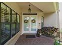 Inviting entry with double glass doors, brick-paved porch, and decorative accents, enhanced by natural light from large windows at 621 High Point Dr, Mount Dora, FL 32757