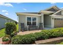 Inviting front porch featuring rocking chairs, bench seating, and lush landscaping at 6243 Danielson Loop, The Villages, FL 32163