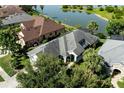 Aerial view of home with a screen enclosed porch, nestled near a lake with lush landscaping at 7873 Crosswinds Way, Mount Dora, FL 32757