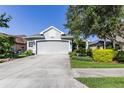 A lovely home with a gray two-car garage, meticulous landscaping and concrete driveway at 7873 Crosswinds Way, Mount Dora, FL 32757