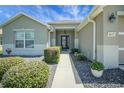 Well-maintained front exterior with manicured bushes, walkway, and decorative flower pots at 8652 Se 133Rd Ln, Summerfield, FL 34491