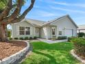 Charming single story home featuring mature trees, landscaped yard, paved pathway, and attached two car garage at 8980 Se 178Th Muirfield Pl, The Villages, FL 32162