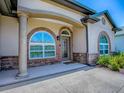 Charming front porch featuring stone accents, arched windows and an attractive, decorative front door at 10994 Se 168Th Loop, Summerfield, FL 34491