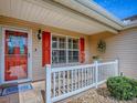 Charming front porch with seating, a red door, and detailed trim at 1206 Thompson Ave, The Villages, FL 32162