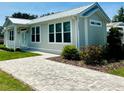 A beautiful single story home featuring large windows, a metal roof, and a patterned brick walkway at 12077 Lakeshore Way, Oxford, FL 34484