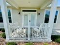Inviting front porch featuring rocking chairs, white railings, and a brick-paved floor at 12077 Lakeshore Way, Oxford, FL 34484