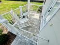 Inviting porch featuring gray brick, white rocking chairs, table, and railing with gate at 12077 Lakeshore Way, Oxford, FL 34484
