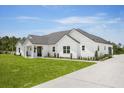 Exterior of a stunning modern farmhouse featuring lush green lawn, landscaping, and a concrete driveway at 12565 Cynthia Ln, Clermont, FL 34715