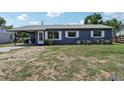 View of a single story home with gray exterior, white trim, metal roof and car port at 1406 Hope Ct, Tavares, FL 32778