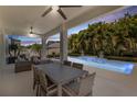 Inviting covered patio with stylish outdoor seating and dining area next to a pool with cascading water feature at 14907 Guava Bay Dr, Winter Garden, FL 34787