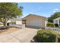 Inviting home featuring a tidy lawn, attached garage, and classic white picket fence at 1615 Navidad St, The Villages, FL 32162