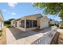 A charming home featuring a covered, screened porch, garage, and manicured lawn at 1615 Navidad St, The Villages, FL 32162
