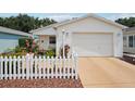 Inviting front exterior featuring a cozy porch with a white picket fence and colorful flowerbeds at 1728 Morelos Rd, The Villages, FL 32159