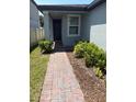 Beautiful front entrance with a brick pathway, manicured shrubs, and a freshly painted door at 1808 Carnostie Rd, Winter Haven, FL 33884