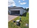 Single-Gathering home featuring a two-car garage, brick driveway, and well-maintained landscaping at 1808 Carnostie Rd, Winter Haven, FL 33884