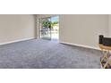 Spacious living room featuring neutral walls, plush carpeting, and a sliding glass door to the balcony at 2423 Branch Way # 207, Maitland, FL 32751